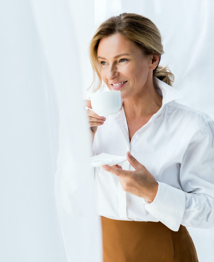 Woman wearing a white top and holding a mug